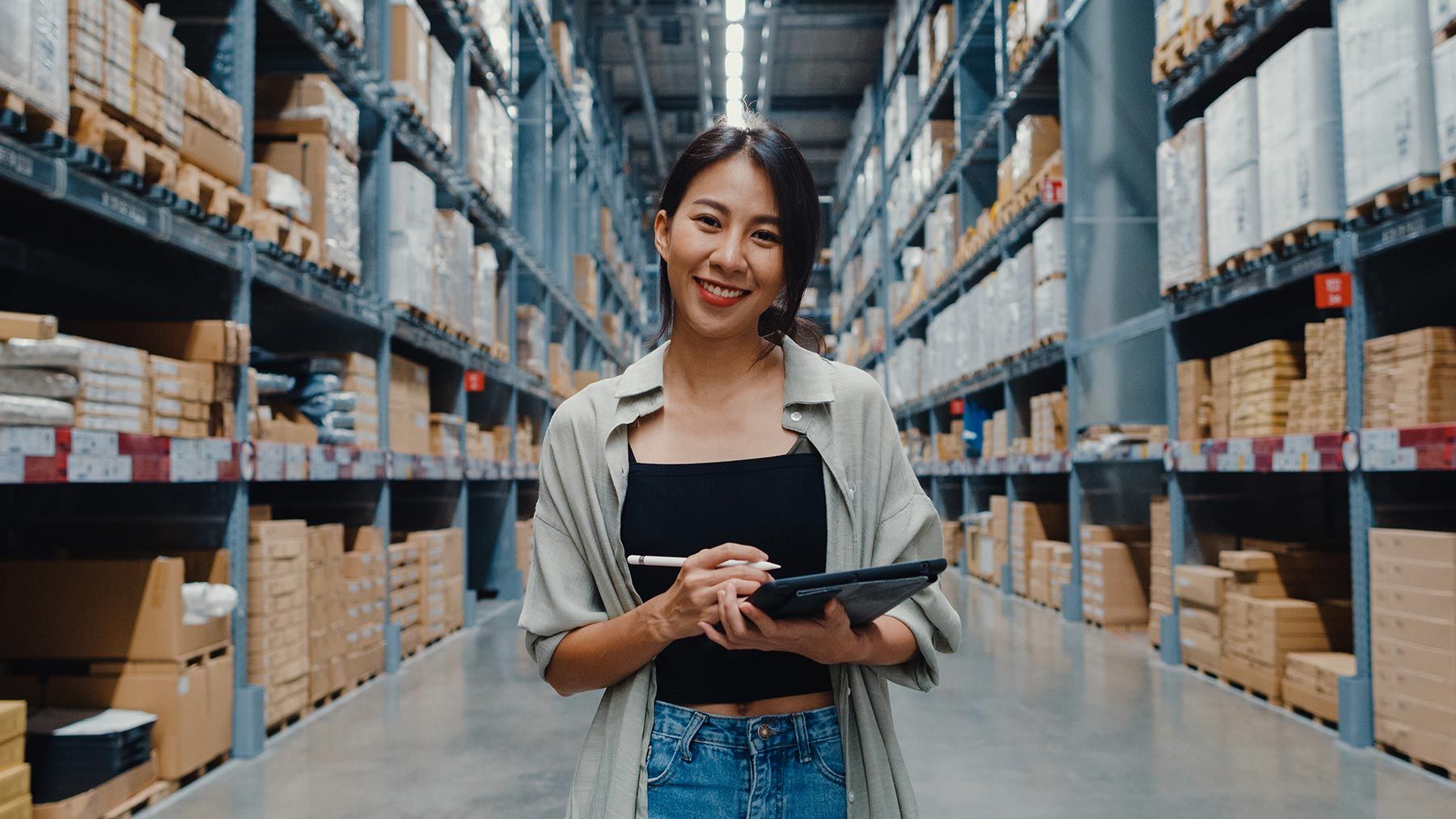 Woman working in warehouse with ipad wide shot